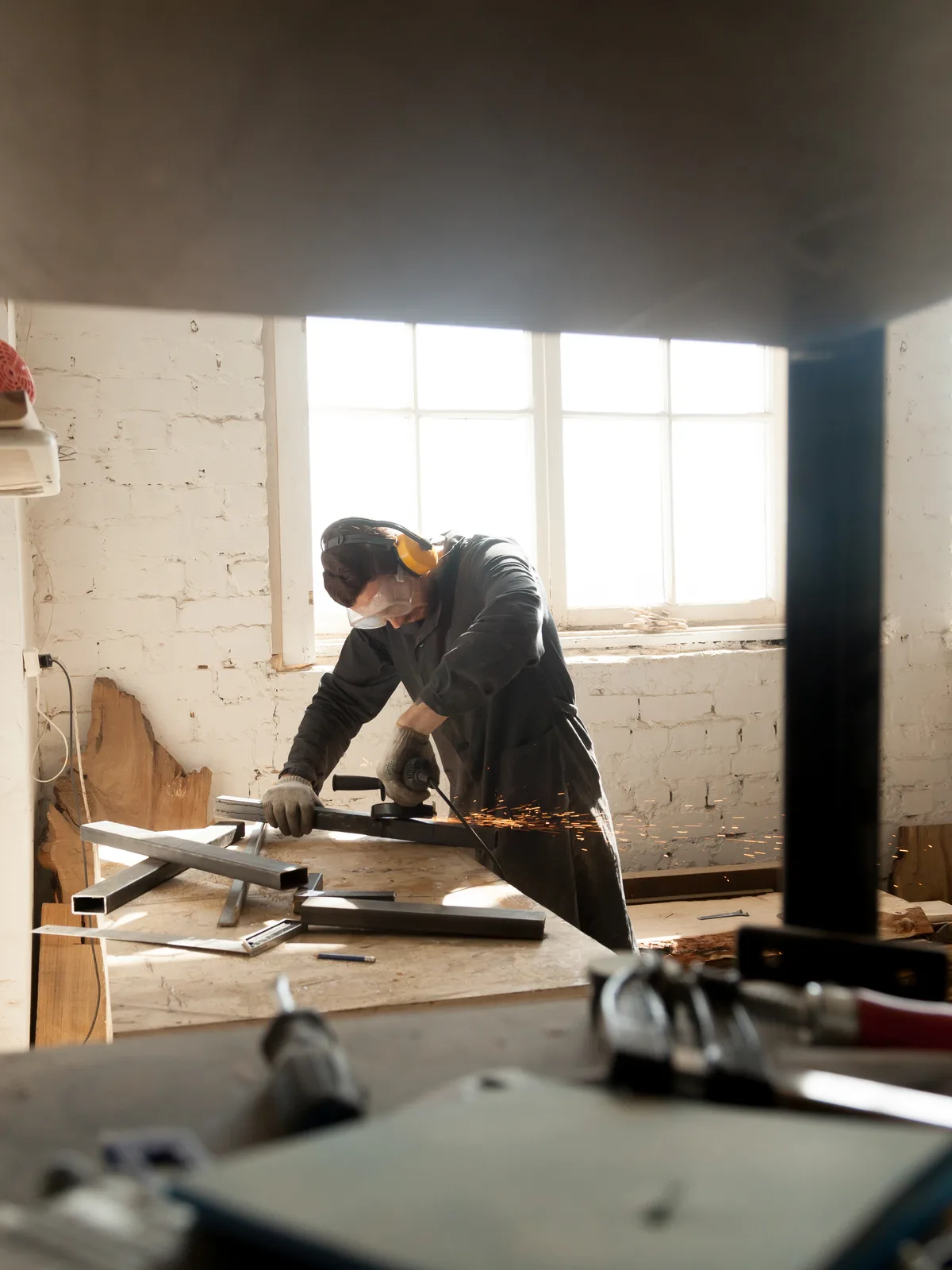 Artisan au travail en atelier, découpe de pièces métalliques